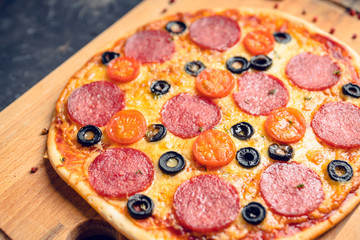 Fresh pepperoni pizza served on the rustic background. Selective focus. Shallow depth of field.