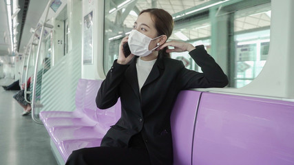 Businesswoman are using their smartphones while traveling on the train to work while the coronavirus is spreading.
