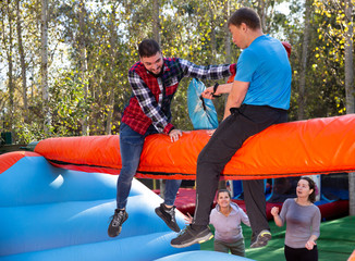 Guys having funny wrestling by pillows in park