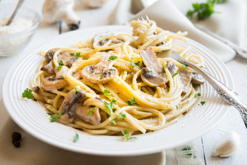 Spaghetti pasta with mushrooms, creamy sause and parsley on white