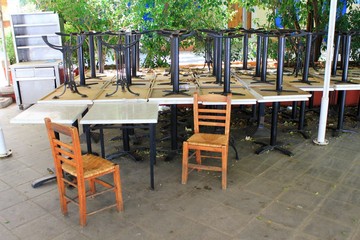 Athens, Greece, May 6 2020 - Tables and chairs stacked outside closed cafe-restaurant during the Coronavirus lockdown.