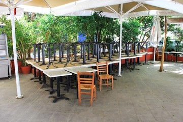 Athens, Greece, May 6 2020 - Tables and chairs stacked outside closed cafe-restaurant during the Coronavirus lockdown.