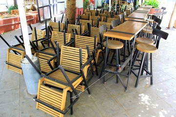 Fototapeta na wymiar Athens, Greece, May 6 2020 - Tables and chairs stacked outside closed cafe-restaurant during the Coronavirus lockdown.
