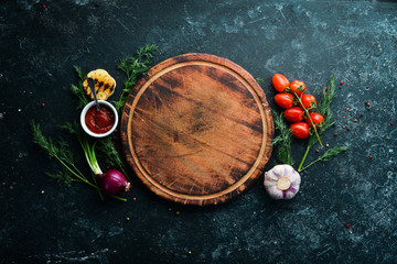 Black kitchen background. Kitchen board, vegetables and spices on a black stone background. Top view.