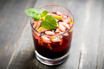 Old fashioned cocktail with blackberry liqueur and apple slices on rustic background. Selective focus. Shallow depth of field.
