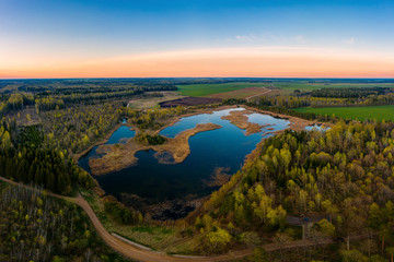 Fototapeta na wymiar Aerial view of a pond surrounded by forest at sunset