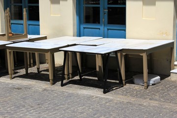 Athens, Greece, May 6 2020 - Tables and chairs stacked outside closed cafe-restaurant during the Coronavirus lockdown.