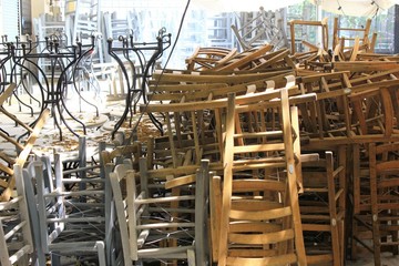 Athens, Greece, May 6 2020 - Tables and chairs stacked outside closed cafe-restaurant during the Coronavirus lockdown.