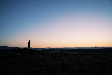 Fototapeta na wymiar Silhouette of a person taking a photo of the horizon