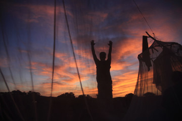 człowiek witający wschód słońca w afryce stojący między namiotami z moskitier