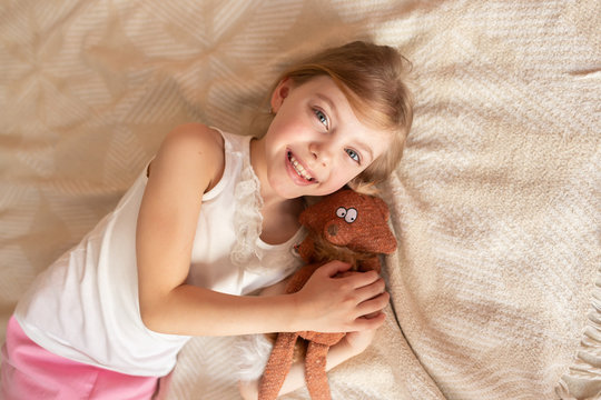 Cute little girl with a soft toy on the couch
