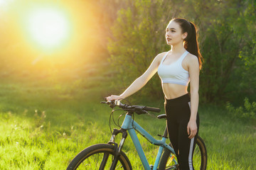 Fototapeta na wymiar Young nice woman has a bike ride in a park on sunset. copy space