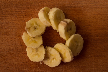 slices of yellow banana laid out in a circle on a wooden board