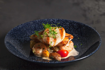 Restaurant menu. Seafood with baked potatoes. Calamari and shrimp on the grill. Cherry tomatoes with micro-green sauce.Ceramic ware.