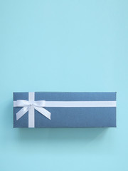 Classic blue gift box with white ribbon and greeting list on a blue background. Copy space for text. Selective focuse. Invitation card