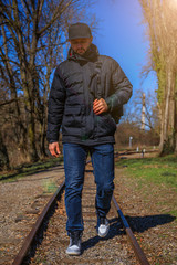 Man walk away on railroad with warm light. Selective focus on sunny day. Traveler man with backpack on railway.