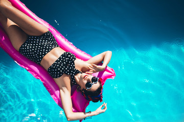 
Beautiful girl by the pool with long dark hair and make-up resting at a spa resort. In a black...