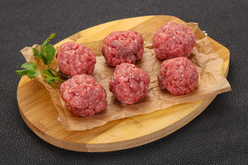 Raw meatball over wooden background