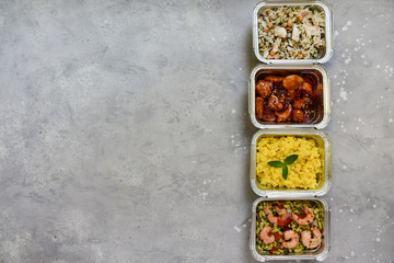 Food delivery. Different aluminium lunch box with healthy food risotto, chicken with chickpeas and rice, salmon and spinach, chicken teriyaki, shrimp and green beans. airline meals snacks. takeaway