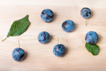 Ripe plums on a wood texture background