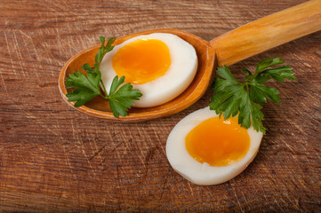 Boiled egg in a wooden spoon on a board