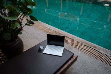 Laptop at the swimming pool and smartphone