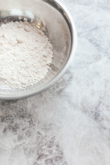 A metal bowl with wheat flour on the table