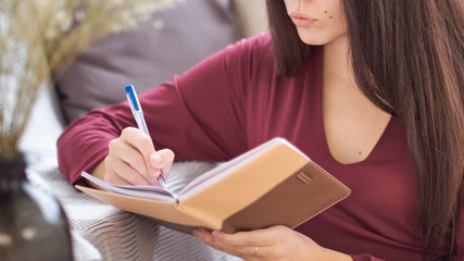 Close up partial portrait female author at home writing in journal