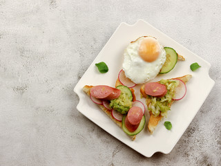 Egg and sausage sandwiches on a white rectangular plate on a light gray background. Top view, flat lay