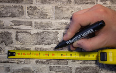 We measure the yellow roll on a brick wall and make marks with a marker for further work..