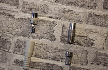 Metal and plastic plug for the antenna in the televisor on the background of a brick wall..