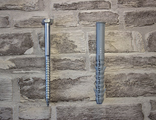 Anchor plug with universal wrench screw against a brick wall.