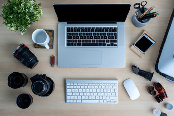 Work table, creative graphics, photographer work, computer office desk. Laptop, smart phone, drawing booklet, notebook, pencil, plant, lens, mug, ruler, flash drive, mouse, keyboard, desk, from above.