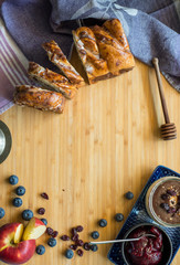 Cocoa walnut cake on bamboo table, decorated with blueberries, chocolate cream and jam.