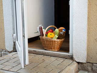 Basket of food on the doorstep. Concept of food delivery to those in need during the pandemic.