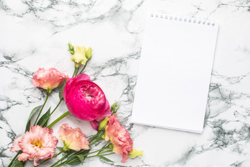 Notebook and pink flower bouquet on marble background