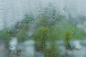 grey rainy droplets on a window glass. surface. drops on window shield in a rainy days  in a city. stormy weather.  rainy season. stormy weather. isolation sad depression concept. rainy season.
