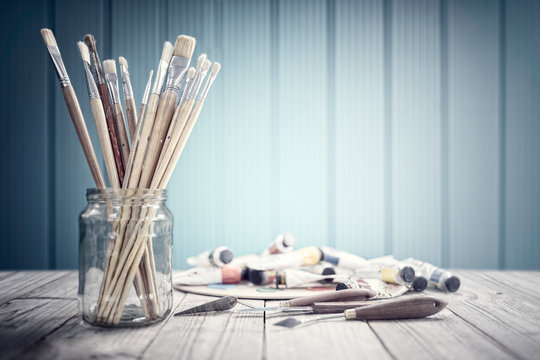 Paint brushes in a glass jar art and craft background - Powered by Adobe