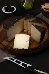 Table with cured cheese, on black background