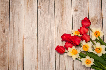 Fototapeta na wymiar Flower composition. A beautiful bouquet of bright spring red tulips and yellow daffodils on a wooden background. Free space.