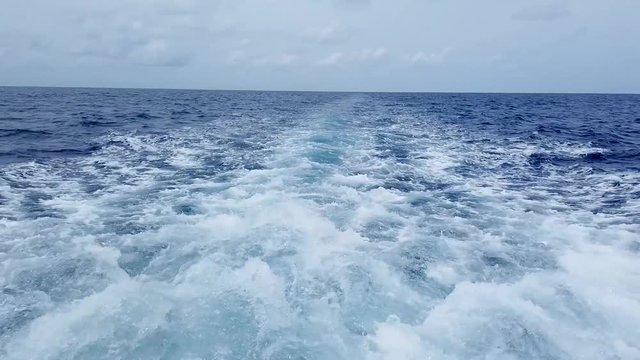 water splashes on the back of the boat while sailing on seawater on a cloudy day in Maldives