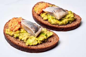 Fresh rye bread with herring and avocado.