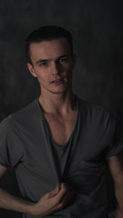 Naklejka premium young sports guy takes off his shirt looking at the camera