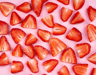 Sliced strawberry on mild pink paper background                               