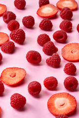 Raspberries and strawberries on pink paper background