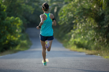 Young fitness woman running on  tropical forest trail