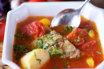 Delicious hearty soup with meat, potatoes and vegetables on the table in the restaurant.
