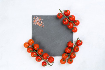 Gray slate board with vine tomatoes, pink salt, light over cement texture background with copy space. Free space for menu or recipes. Cooking or food background, Top view.