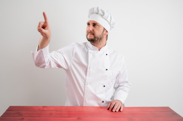 Young male chef in white uniform presses a virtual button