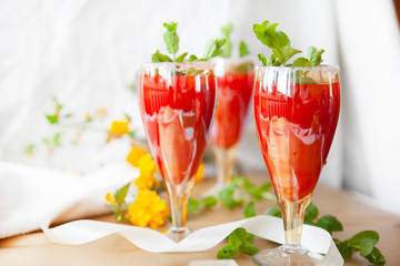 Crystal bakery with a drink, homemade cold juice with mint with fresh berries on a light background. Selective focus.
